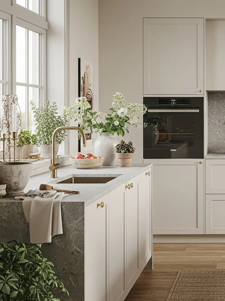 Kök med ramluckor i varm beige ton, marmorstänkskydd och klassiskt välvt fönster