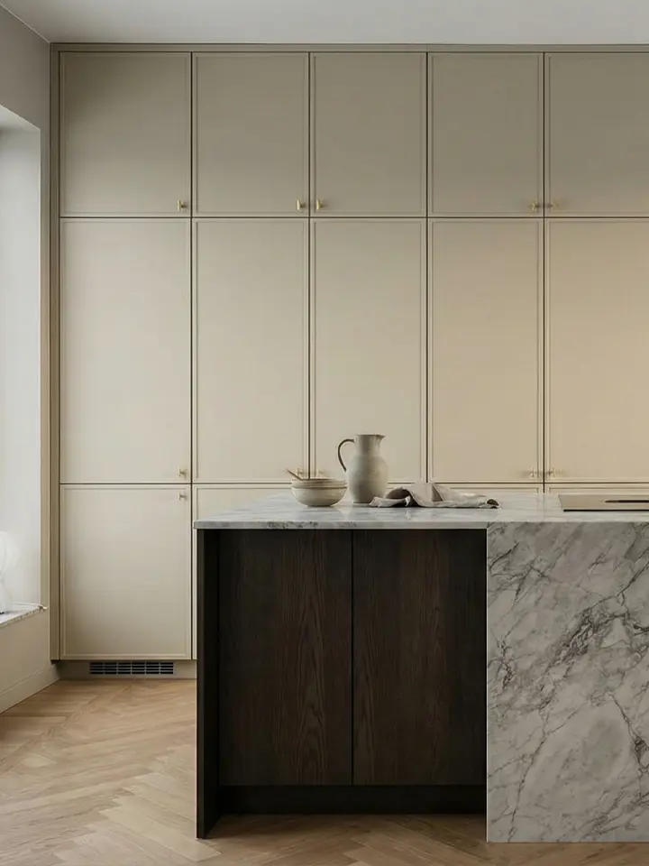 Kök med ramluckor i varm vit kulör, stenbänkskiva och mässingsdetaljer