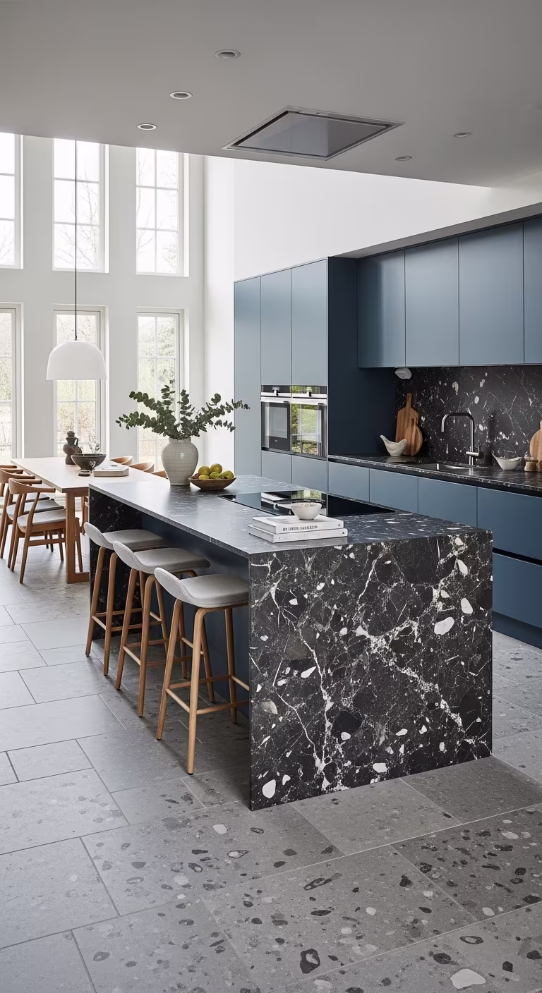 Contemporary kitchen with blue cabinets, black marble island and dining area with wooden chairs.