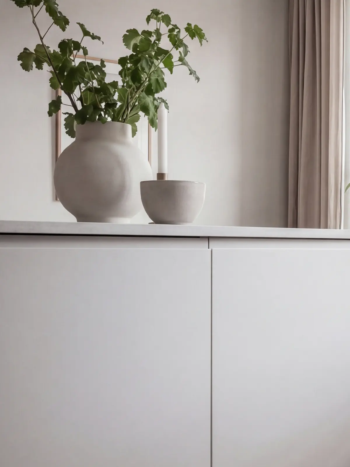 Flow köksluckor i ljus beige med växter, stora fönster, trädetaljer och nordisk inredning.