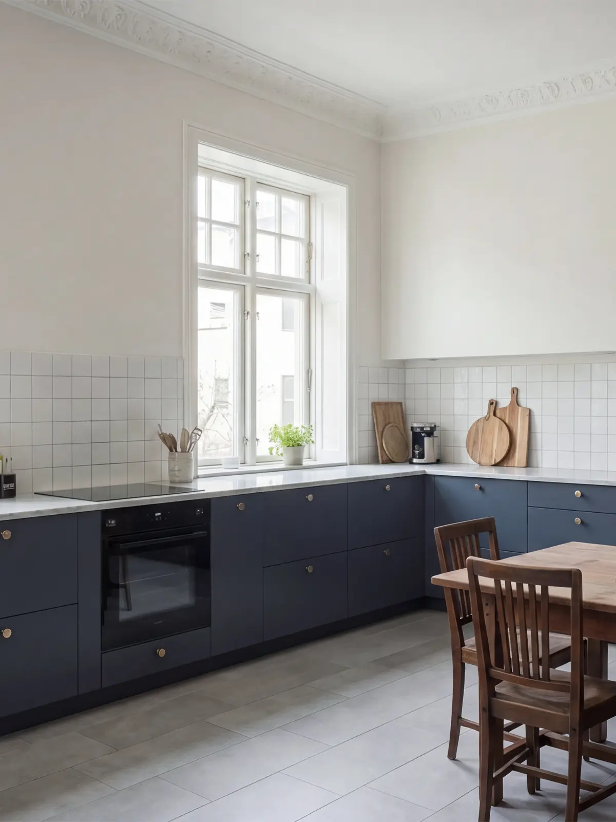 Matplats framför blå förvaringsvägg med köksluckor i Pure, träbord och pendellampa i mässing.