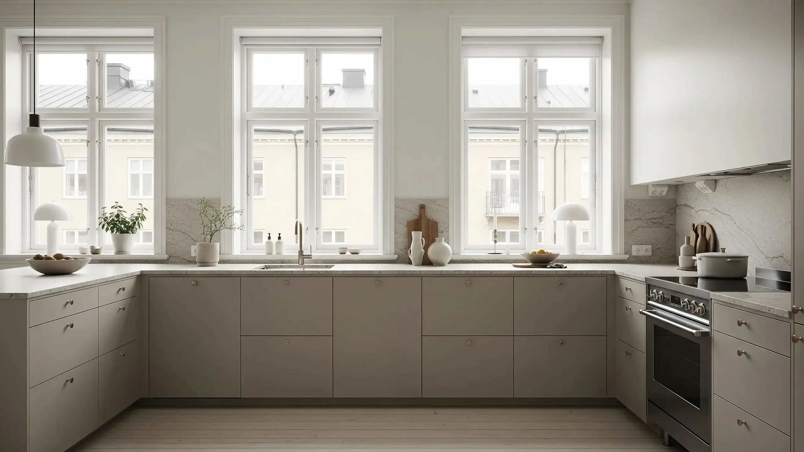 Kök i Off Grey med släta köksluckor i modellen Pure, ljus stenbänkskiva, klassiska fönster och detaljer i mässing.
