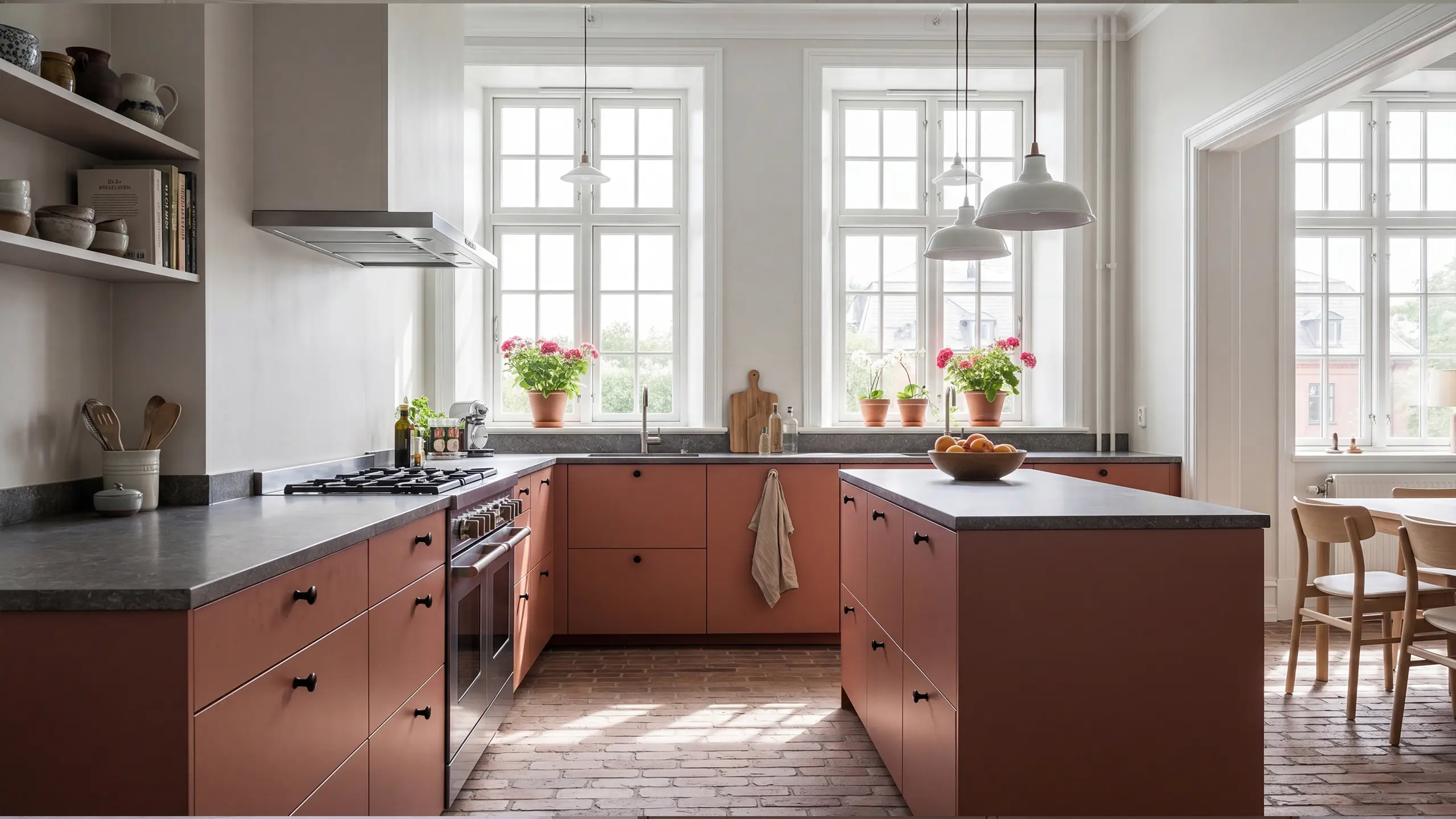 Kök med köksluckor i terracotta i modellen Pure, tegelgolv, grå bänkskiva och klassiska fönster.
