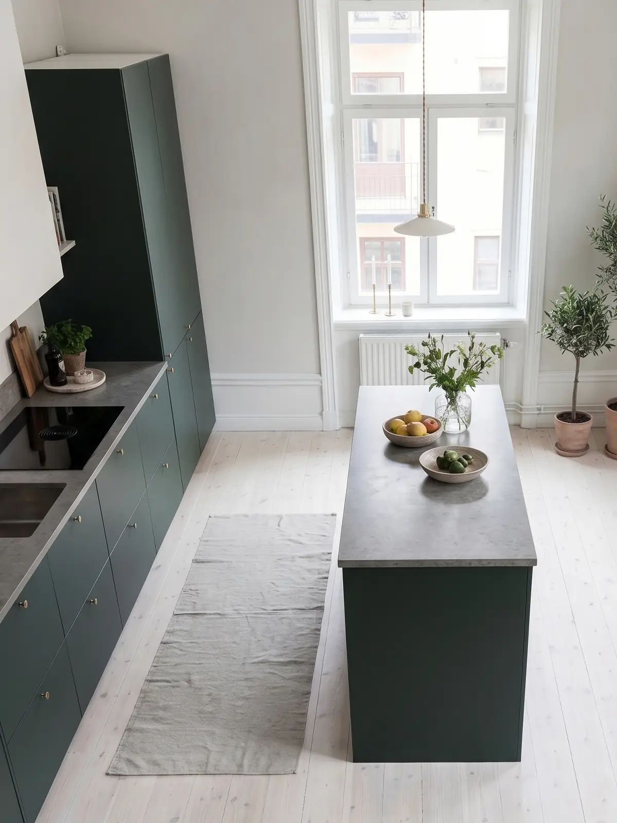 Detalj av släta köksluckor i Pure i Imperial Green med ljus stenbänkskiva och mässingsknopp.