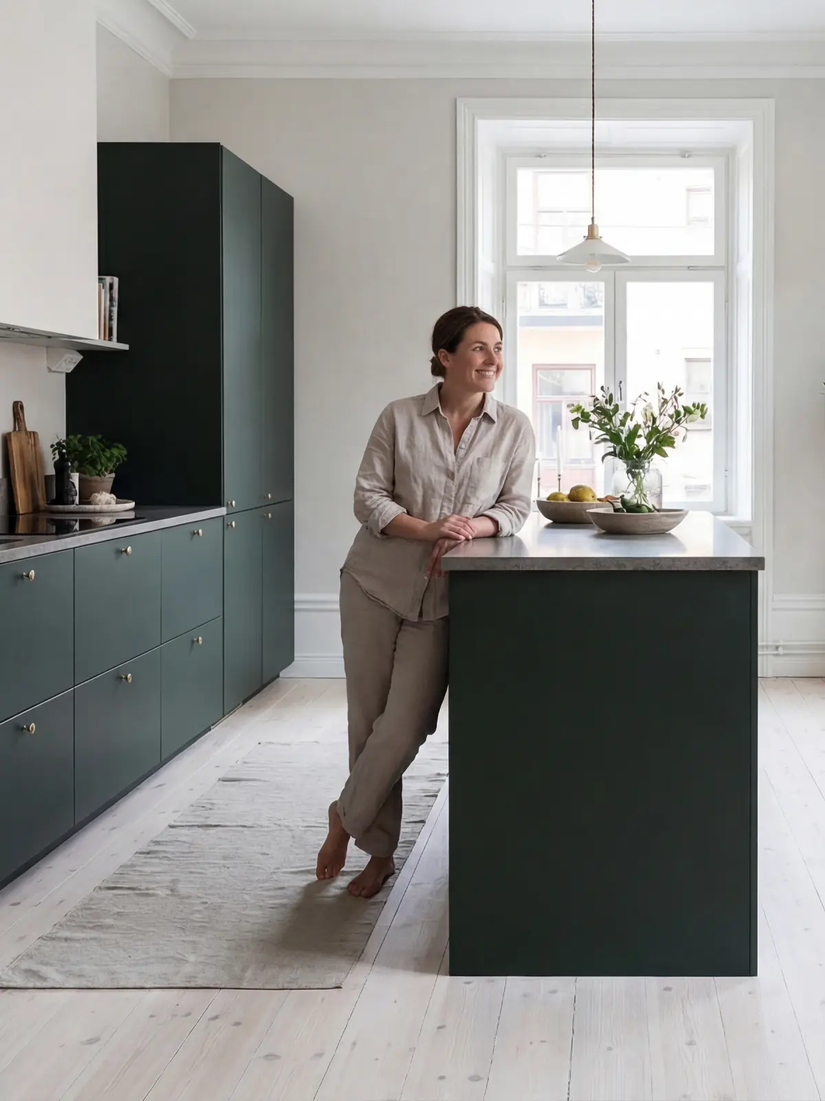 Kök med gröna luckor, ljusa trägolv och minimalistiska detaljer.